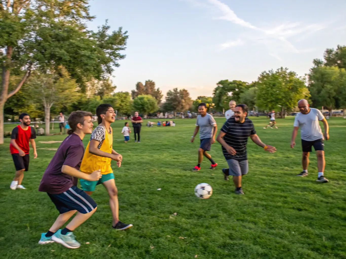 A vibrant image of children and adults playing soccer on a sunny field, showcasing active participation and community spirit in ITON SPORTS AND CULTURE's community sports programs.